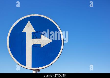 Ein leuchtendes blaues Schild zeigt einen klaren Pfeil, der entscheidend nach rechts zeigt und die Richtung für Fahrzeuge und Fußgänger anzeigt Stockfoto