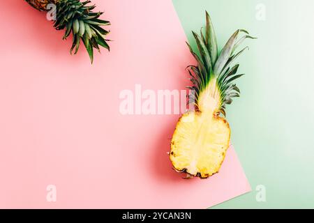 Eine halbe Ananas auf rosa und grünem Hintergrund. Gesundes Essen, Sommerkonzept. Draufsicht, flach, Kopierbereich. Stockfoto