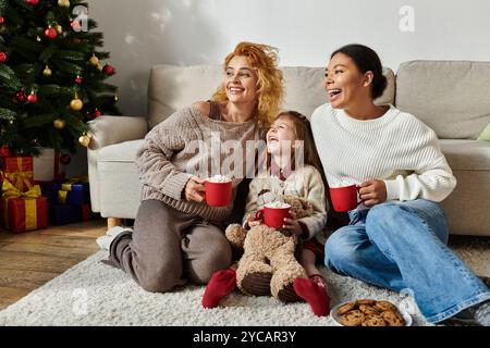 Ein Paar teilt einen gemütlichen Moment mit seiner Tochter, voller Lachen und Wärme. Stockfoto