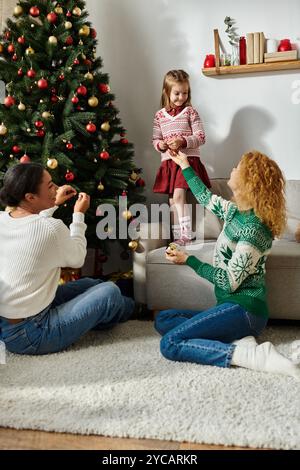 Ein liebevolles Paar teilt zärtliche Momente mit ihrer Tochter, während sie Weihnachten dekoriert. Stockfoto