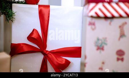 Ordentlich verpackte Geschenkboxen unter dem modernen Weihnachtsbaum in einem Haus, ergänzt durch Weihnachtsschmuck, eine festliche Neujahrsdekoration. Stockfoto