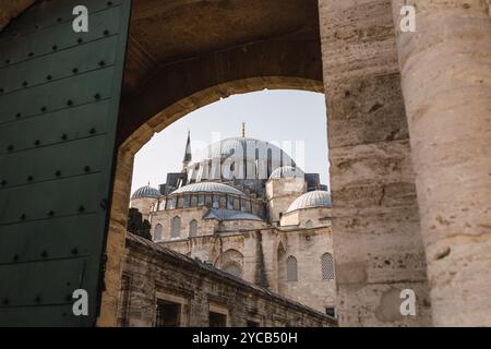 Ein inspirierender Blick unter einem alten Steinbogen, der die berühmten Kuppeln und Minarette der Suleiman Moschee in Istanbul umrahmt. Stockfoto