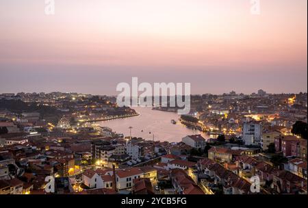 Ein Panoramablick auf Porto bei Sonnenuntergang mit einem pulsierenden Himmel und der beleuchteten Stadtlandschaft am Ufer des Flusses Douro Stockfoto