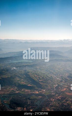 Ein atemberaubendes Luftbild, das die majestätischen Alpen und die üppige Flickenteppellandschaft darunter vom Fenster eines Flugzeuges aus einfängt Stockfoto