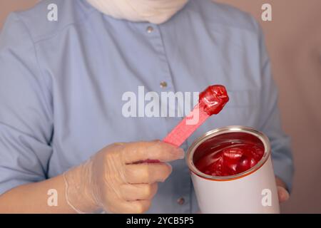 Wachssitzung in einem Schönheitssalon mit grünem Wachs, das während der Behandlung auf die Haut aufgetragen wird Stockfoto