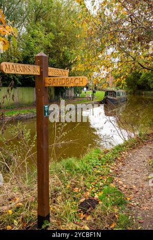 Wegweiser auf dem Trent und Mersey Kanal mit verankertem Schmalboot im Dorf Wheelock Cheshire Stockfoto