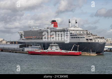 Die Red Funnel Isle of wight Fährschiffe MV Red Kestrel in Southampton legen neben dem Cunard Kreuzfahrtschiff Queen Mary 2 im Hafen von Southampton an. Stockfoto