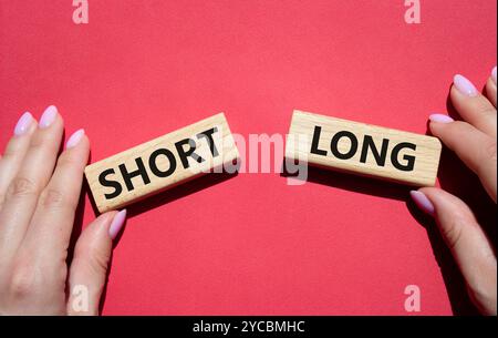 Symbol kurz vs lang. Konzeptwort kurz vs lang auf Holzblöcken. Geschäftsmann Hand. Schöner roter Hintergrund. Business und kurz- vs Langkonzept. Cop Stockfoto