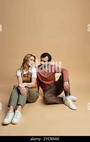 Ein Paar teilt einen warmen Moment, sitzt nebeneinander auf einem glatten Boden und lächelt liebevoll. Stockfoto