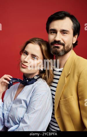 Ein stilvolles Paar steht nahe und lächelt warm, während es seine einzigartigen Modeschöpfe annimmt. Stockfoto
