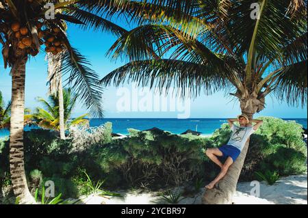 Attraktiver junger Touristenmann, der sich auf Palmen am karibikstrand entspannt. Faule Zeit, Sommerurlaub Konzept Stockfoto