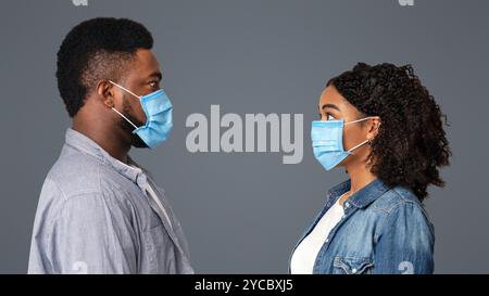 Viruswarnung. Profilporträt Des Verängstigten Schwarzen Paares In Schutzmasken Stockfoto