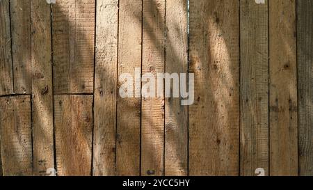 Fragment eines alten Holzzauns im Sonnenlicht als leere Vorlage oder als Hilfsmittel für grafische Gestaltung, raue Dielenhintergrundstruktur von alten unplanierten Brettern Stockfoto