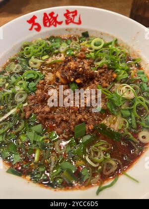 Scharfe Dan Dan Dan Dan Nudeln nach Sichuan-Art, garniert mit Schweinehackfleisch, Zwiebeln und einer reichhaltigen Chili-Ölsauce, serviert in einer traditionellen Schüssel Stockfoto