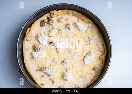 Rezept für französische Quiche lorraine Pie. In einer Auflaufform Pilze, Käse und Hähnchenstücke auf den Teig geben. Hochwertige Fotos Stockfoto
