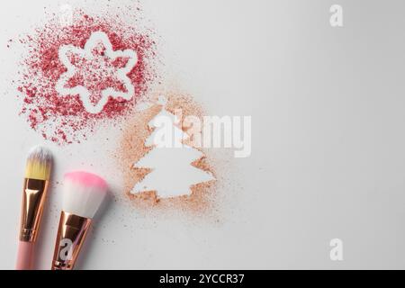 Weihnachtsdekorationen aus Puder und Rouge in der Nähe von Make-up-Pinseln auf weißem Hintergrund, flach gelegt. Leerzeichen für Text Stockfoto