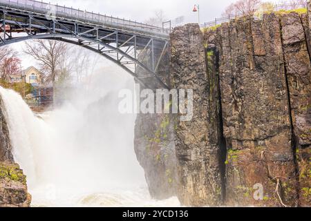 Paterson Great Falls im Frühjahr, mit Nebel, der von mächtigem Wasser über Klippen unter bewölktem Himmel steigt. New Jersey. USA. Stockfoto