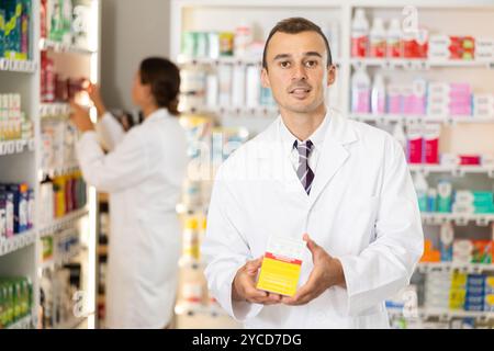 Junger männlicher Apotheker, der die Zubereitung im Karton anbietet Stockfoto