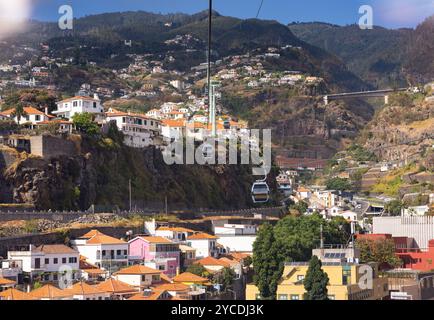 Seilbahn mit Hütten über der Stadtlandschaft von Funchal und Monte mit den Bergen im Hintergrund. Insel Madeira, Portugal Stockfoto