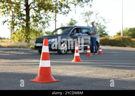 Der Prüfer, der den Schüler vor der Prüfung auf der Fahrschule anweist, konzentriert sich auf den Verkehrskegel Stockfoto