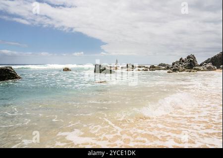 Ein Boot, das auf der Insel Reunion vor den felsigen Ufern des Grand Fond Beach an der Westküste der Insel durch den Indischen Ozean segelt Stockfoto