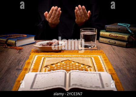 Viele Dattelpalmen stehen auf Schüsseln, Tellern und Tassen Wasser, und der Koran steht auf Holztischen, um auf die Zeit des Iftar zu warten, mit dem Konzept des ramadan Stockfoto
