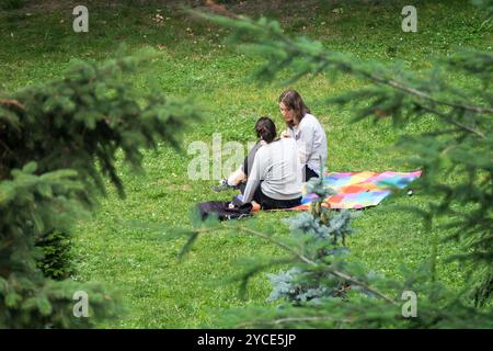 Zwei junge Frauen sitzen auf einer Decke im Park Stockfoto