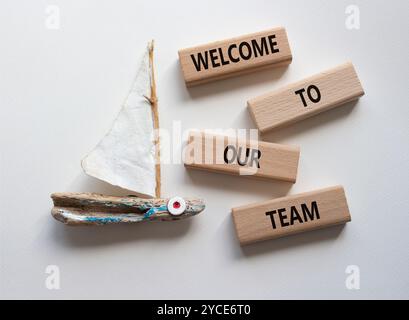 Willkommen bei unserem Teamsymbol. Concept Words Willkommen bei unserem Team auf Holzblöcken. Schöner weißer Hintergrund mit Boot. Business und Willkommen in unserem Team Stockfoto