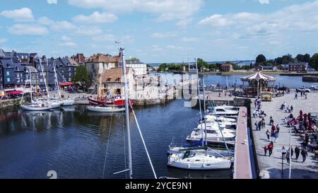 Blick aus der Vogelperspektive auf die Yachten und die Brücke im alten Hafen von Honfleur, einem Resort und einer antiken Stadt in der Normandie, Leute zu Fuß in der Nähe. (Nicht erkennbar gemäß Stockfoto