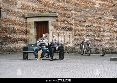 Utrecht, Niederlande, 4. August 2016: Zwei Männer sitzen auf einer Verlagsbank im historischen Zentrum von Utrecht, Niederlande Stockfoto