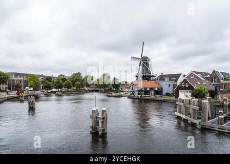 Haarlem, Niederlande, 3. August 2016: Malerische Stadtlandschaft mit wunderschönem traditionellen Haus, Windmühle und Schiffen im Kanal von Haarlem Stockfoto