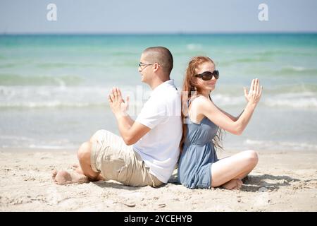 Paar am Strandsand sitzen und Übungen Stockfoto