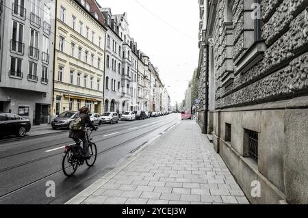 München, 05. Mai 2015: Straße im Zentrum der Stadt mit einer Radfahrerin. Die Stadt ist die Hauptstadt Bayerns und ein bedeutendes Kunstzentrum Stockfoto