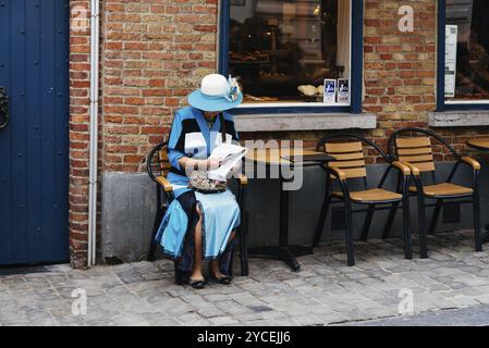 Brügge, Belgien, 29. Juli 2016: Alte, elegante Frau in blau gekleidet auf einer Terrasse in der Straße von Brügge, Europa Stockfoto