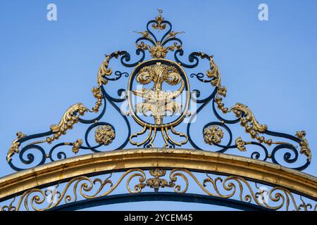 Detail des antiken goldenen Dekors mit Krokodil und Palme - Wappen der Stadt - auf dem Zaun von Jardins de la Fontaine, Nîmes, Gard, Frankreich Stockfoto