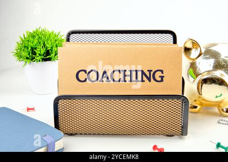 Geschäftskonzept. Der Satz, Text, Wortwahl COACHING ist auf Papier in einem schwarzen Ständer auf hellem Hintergrund geschrieben. Stockfoto