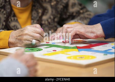 Gruppe von nicht erkennbaren Seniorinnen, die das klassische Spiel Ludo oder Parchis im Pflegeheim spielen. Stockfoto