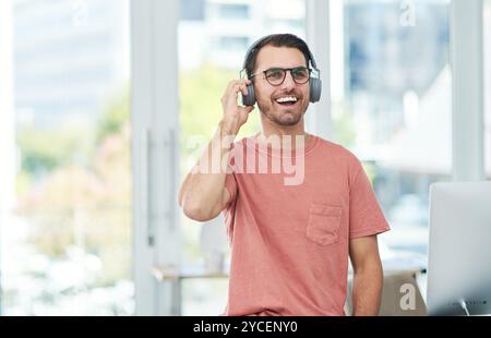 Mann, Kopfhörer und hören Sie mit einem Lächeln im Büro, Streaming und Abonnement mit Reflexion beim Medienstart. Person, Musik und mit Sound zufrieden Stockfoto