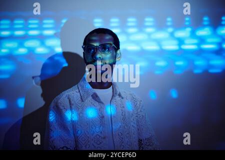 Porträt eines Brillenmannes, der mit Blaulichteffekten steht Stockfoto