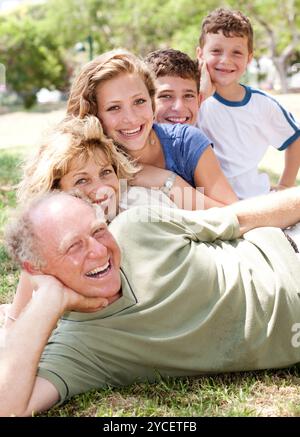 Generationsübergreifende Familie relaxen im Park am sonnigen Tag und lächelt in die Kamera Stockfoto