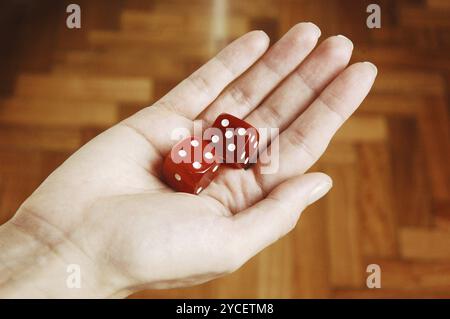 Weibliche Hände halten zwei rote Würfel Stockfoto