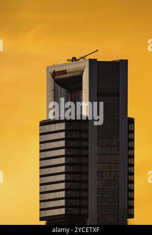 Madrid, Spanien, 17. August 2022: CEPSA Tower im Geschäftsviertel Cuatro Torres. Blick bei Sonnenuntergang mit einem dramatischen leuchtenden gelben Himmel. Teleobjektiv-Ansicht. Sp Stockfoto