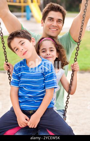 Kinder haben Spaß mit ihrem Vater im Park und lächeln in die Kamera Stockfoto