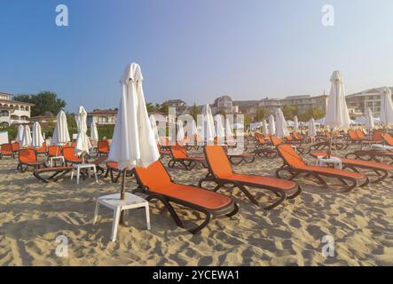 Rote Stühle und Sonnenschirme an einem wunderschönen Strand bei Sonnenaufgang in Sunny Beach an der Schwarzmeerküste Bulgariens Stockfoto