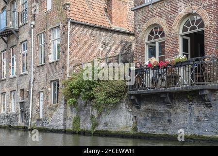 Gent, Belgien, 31. Juli 2016: Menschen sitzen auf einer Restaurantterrasse im Embankment Graslei im historischen Zentrum von Gent mit malerischem Altbau Stockfoto