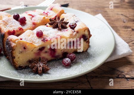 Zwei Stücke Hüttenkäseauflauf mit Preiselbeeren und Gewürzen Zimt und Anis auf einem Teller. Hölzerner Hintergrund Stockfoto