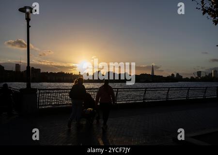 Familienspaziergang bei Sonnenuntergang im Herbst entlang des Flusses Themse Pfade bei Dundee Wharf, Westferry, Docklands, East London, England, UK Stockfoto