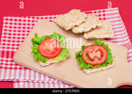Reiskuchen-Sandwiches mit Tomaten und Salat auf Holzbrett. Einfaches Frühstück. Diät-Essen. Schnelle und gesunde Sandwiches. Knäckebrot mit leckerer Füllung. Gesunder Ernährungs-Snack Stockfoto