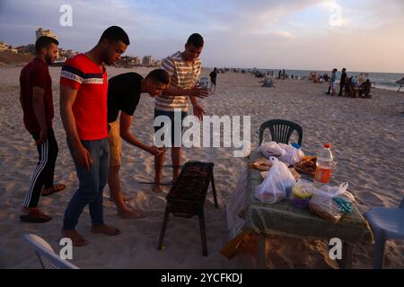 Gaza, Palästina. 16. Mai 2020. Palästinenser genießen den Sonnenuntergang am Meer in Gaza-Stadt. Palästinensern ist es gestattet, während des Ramadan bei Familienversammlungen am Strand ihr iftar- oder Abendmahl zu konsumieren, obwohl im Gazastreifen einige Vorsichtsmaßnahmen getroffen wurden, um die Ausbreitung von COVID-19 zu verhindern. Ausflüge und Picknicks an die Küste und ihre fröhliche Atmosphäre bieten den Gazastreibern eine gewisse Erleichterung von ihren Sorgen über die hohe Armutsrate und Arbeitslosigkeit sowie die häufigen Stromausfälle in der belagerten palästinensischen Enklave Stockfoto