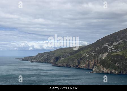 Die dramatischen Klippen der Slieve League treffen auf den Atlantischen Ozean, der durch kontrastierende Texturen und Farben vor einem bewölkten Himmel in Irland hervorgehoben wird Stockfoto